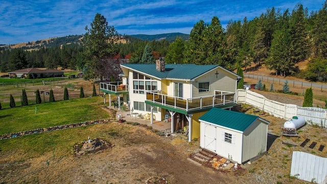 rear view of house featuring a deck with mountain view, a shed, and a lawn