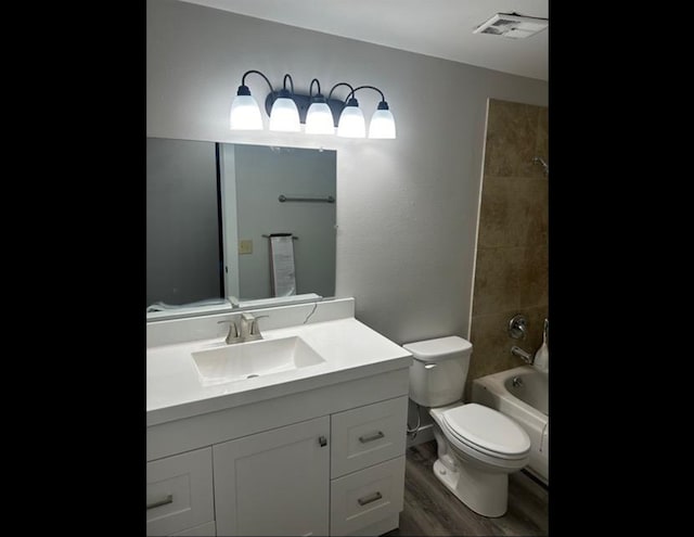 full bathroom with tiled shower / bath, hardwood / wood-style flooring, vanity, and toilet