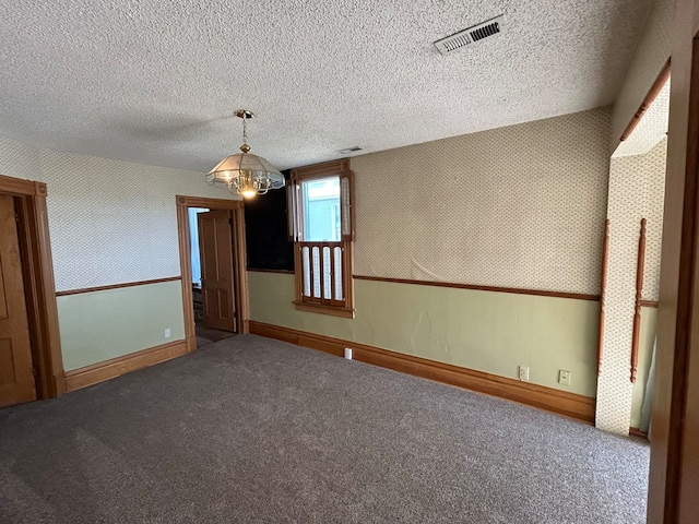 carpeted spare room featuring a textured ceiling and a notable chandelier