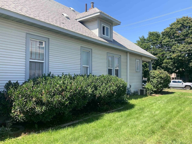 view of side of home with a yard and central AC