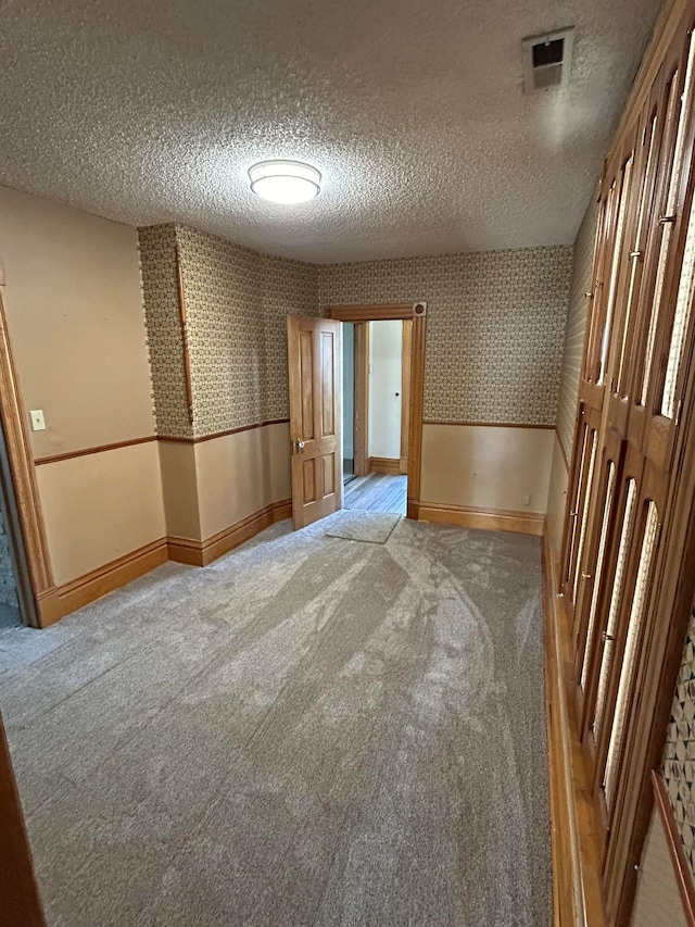 carpeted spare room featuring vaulted ceiling and a textured ceiling