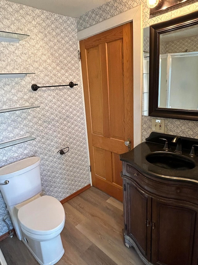 bathroom with toilet, vanity, and hardwood / wood-style floors