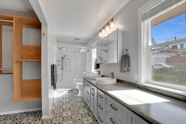 bathroom with tiled shower, vanity, toilet, and tile patterned flooring