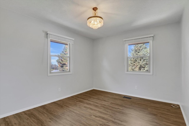 empty room with a wealth of natural light, a textured ceiling, and dark hardwood / wood-style flooring