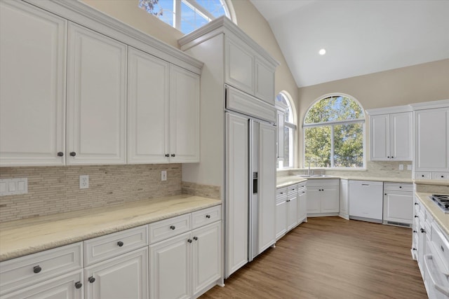 kitchen with white dishwasher, white cabinets, and vaulted ceiling