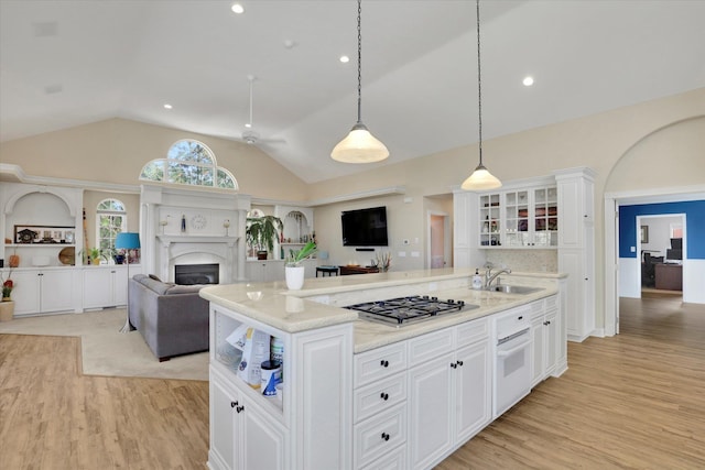 kitchen featuring pendant lighting, sink, vaulted ceiling, and white cabinetry