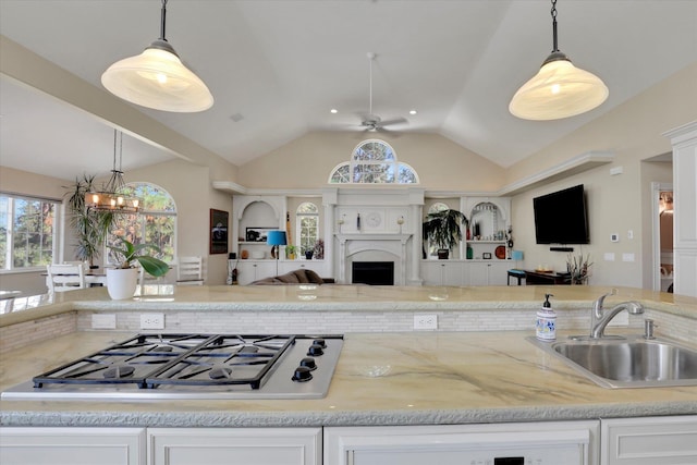 kitchen with vaulted ceiling, stainless steel gas cooktop, decorative light fixtures, and sink