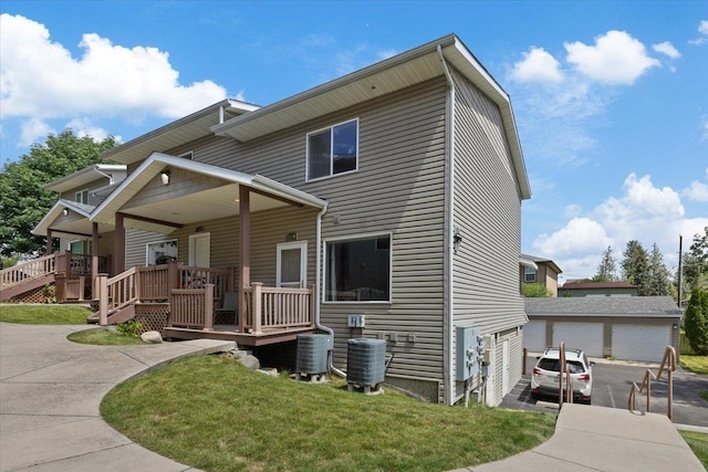 view of front facade featuring a wooden deck, central AC unit, a front yard, and a garage