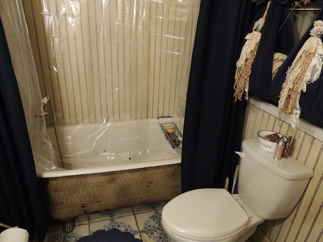 bathroom featuring tile patterned flooring, toilet, and a tub