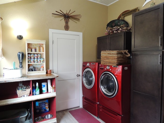 laundry room with light hardwood / wood-style floors, washer and dryer, and cabinets