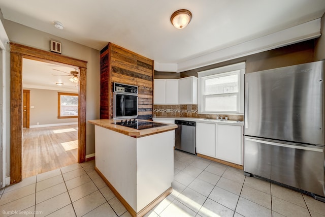 kitchen featuring white cabinets, tasteful backsplash, a healthy amount of sunlight, and black appliances