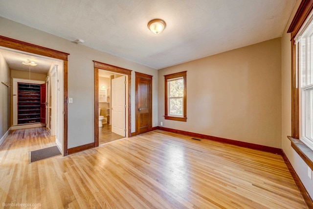 unfurnished bedroom with a spacious closet, light hardwood / wood-style floors, a closet, and ensuite bath