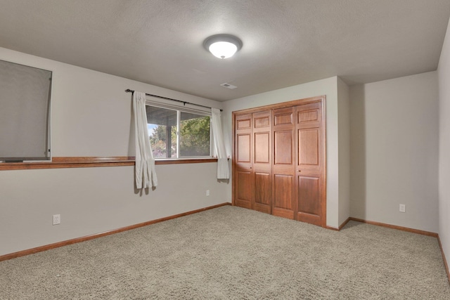 unfurnished bedroom featuring a closet, light colored carpet, and a textured ceiling