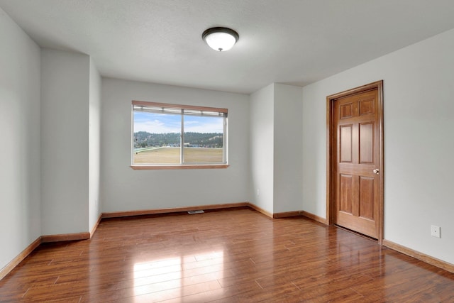 spare room featuring wood-type flooring and a textured ceiling