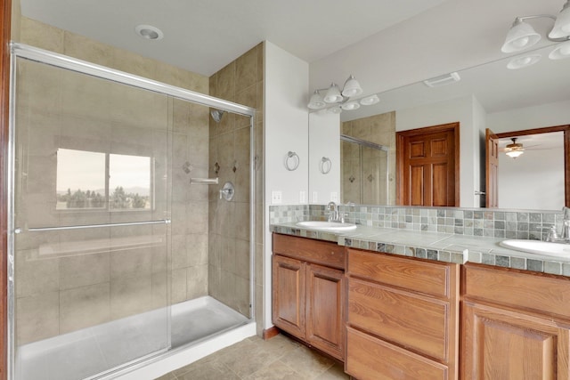 bathroom featuring ceiling fan, vanity, backsplash, tile patterned floors, and a shower with door