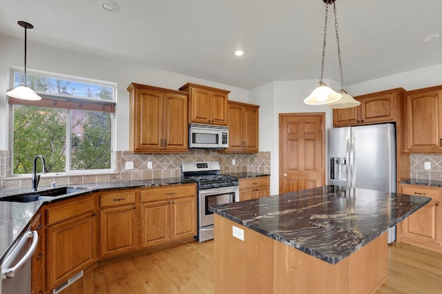 kitchen featuring a center island, sink, hanging light fixtures, light hardwood / wood-style flooring, and appliances with stainless steel finishes