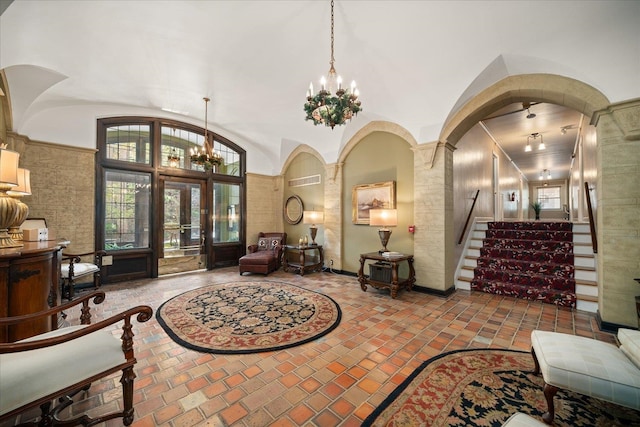 interior space with french doors, a notable chandelier, lofted ceiling, and decorative columns