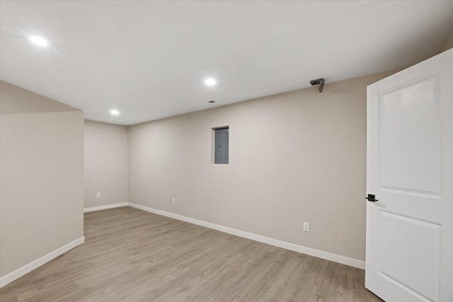 basement featuring light wood-type flooring and electric panel