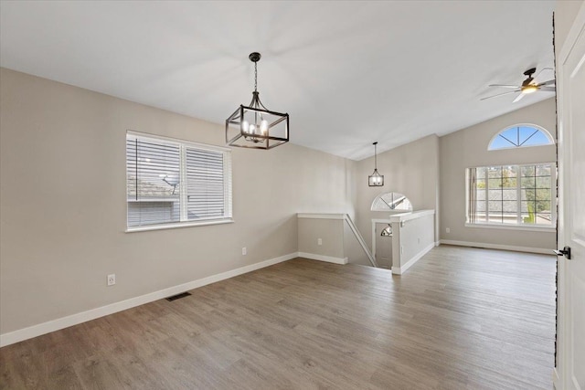 interior space featuring ceiling fan with notable chandelier, hardwood / wood-style flooring, and vaulted ceiling