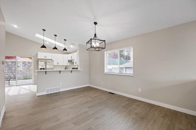 interior space with wood-type flooring, an inviting chandelier, and lofted ceiling with beams