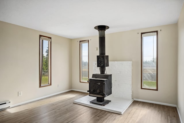 unfurnished living room with a wood stove, light hardwood / wood-style flooring, and plenty of natural light