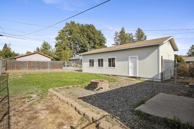 back of house with a yard and an outdoor fire pit