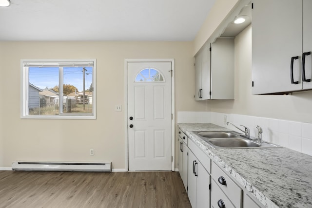 kitchen with light hardwood / wood-style flooring, a baseboard radiator, white cabinetry, and sink