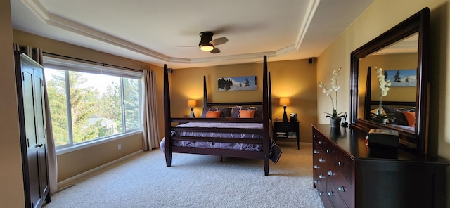 carpeted bedroom featuring a raised ceiling and ceiling fan