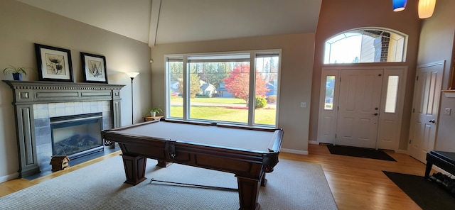 rec room featuring a tiled fireplace, vaulted ceiling, light hardwood / wood-style floors, and billiards