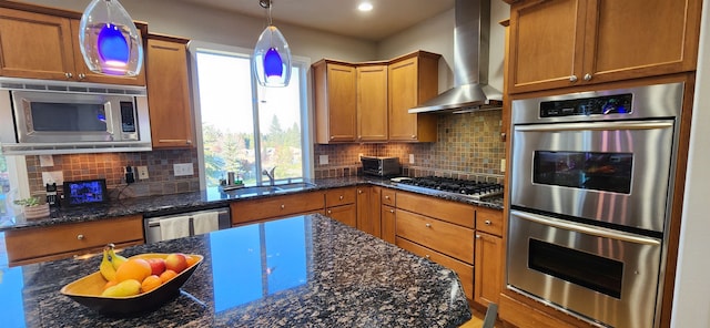 kitchen featuring wall chimney range hood, sink, stainless steel appliances, and tasteful backsplash