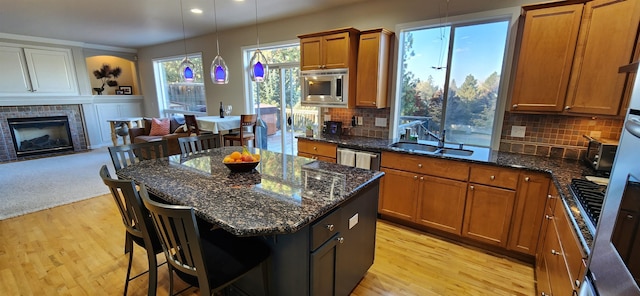 kitchen with tasteful backsplash, light wood-type flooring, decorative light fixtures, and a breakfast bar