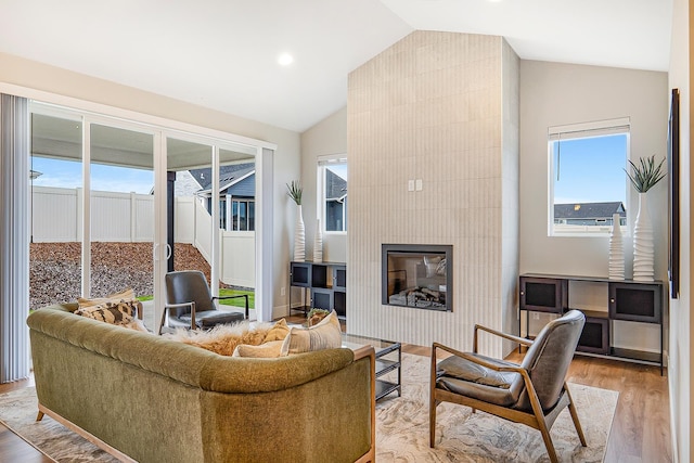 living room with hardwood / wood-style floors, vaulted ceiling, and a large fireplace