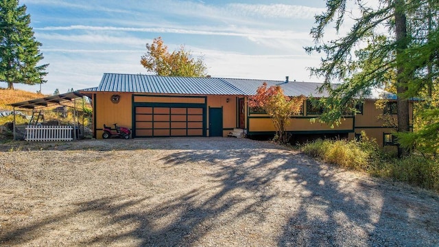 view of front of home featuring an attached garage, metal roof, and driveway