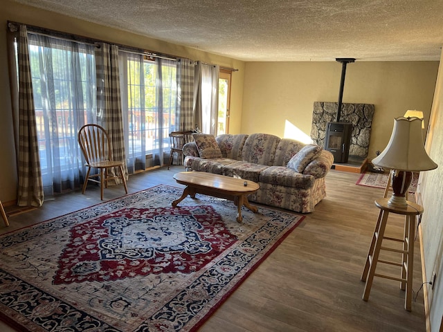 living area with a wood stove, wood finished floors, and a textured ceiling