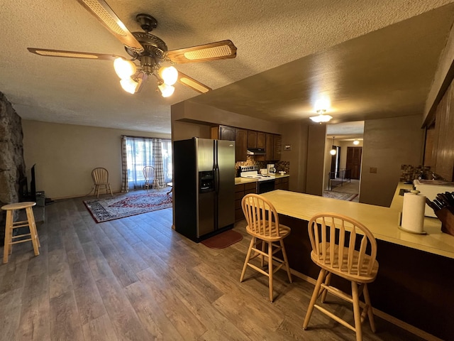 kitchen with ceiling fan, a textured ceiling, a peninsula, stainless steel fridge, and electric stove