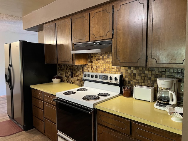 kitchen with light countertops, a textured ceiling, under cabinet range hood, backsplash, and electric range