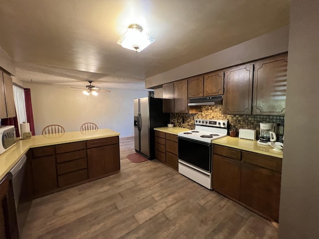 kitchen featuring ceiling fan, appliances with stainless steel finishes, under cabinet range hood, light countertops, and decorative backsplash