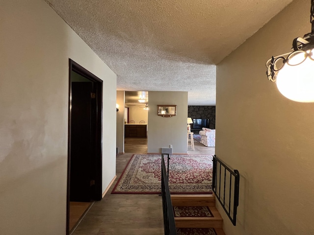 hallway with a textured ceiling and wood finished floors