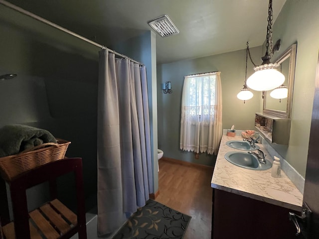 bathroom featuring visible vents, curtained shower, a sink, double vanity, and wood finished floors