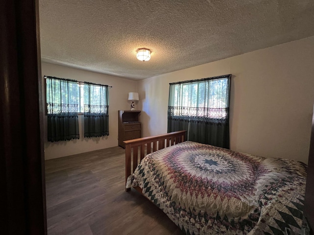 bedroom featuring a textured ceiling, multiple windows, and dark wood finished floors