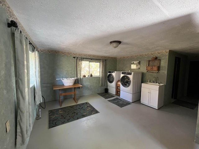 clothes washing area featuring washing machine and dryer, a textured ceiling, a sink, and cabinet space