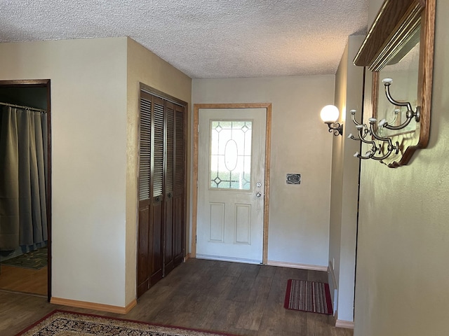 entrance foyer featuring dark wood-type flooring, baseboards, an inviting chandelier, and a textured ceiling