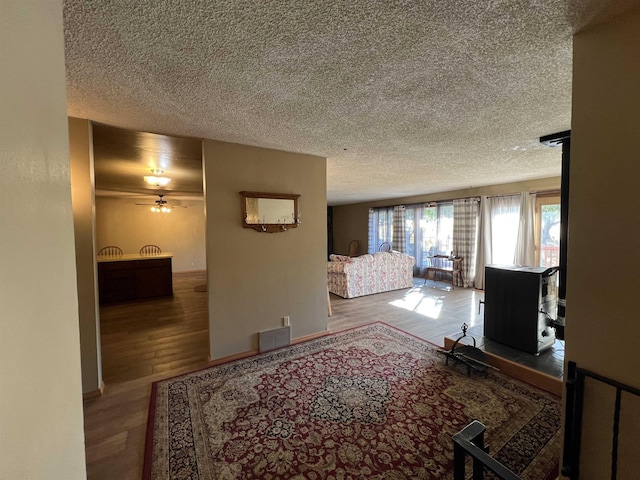 hall with visible vents, wood finished floors, and a textured ceiling