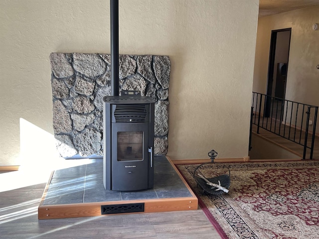interior details featuring a wood stove, wood finished floors, heating unit, and a textured wall