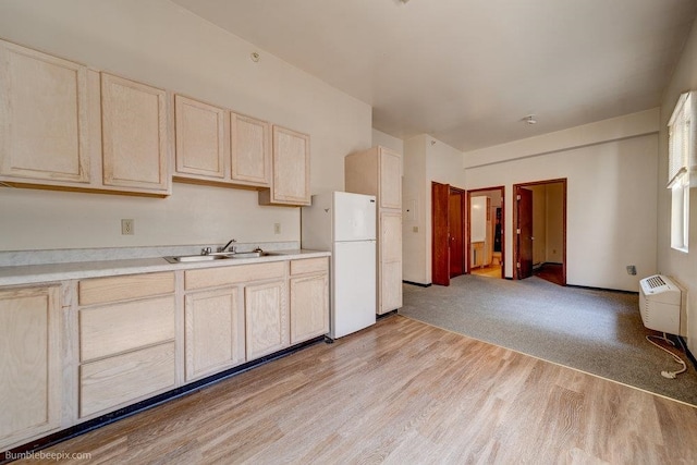 kitchen with light wood-type flooring, light brown cabinetry, sink, and white refrigerator