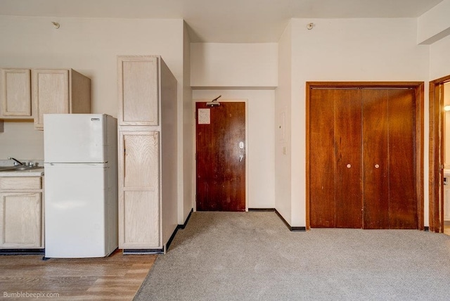 kitchen featuring white fridge, light hardwood / wood-style flooring, light brown cabinetry, and sink