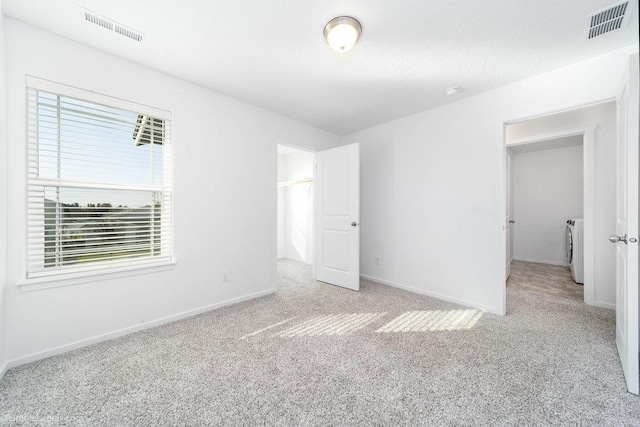 unfurnished bedroom with washer / clothes dryer and light colored carpet