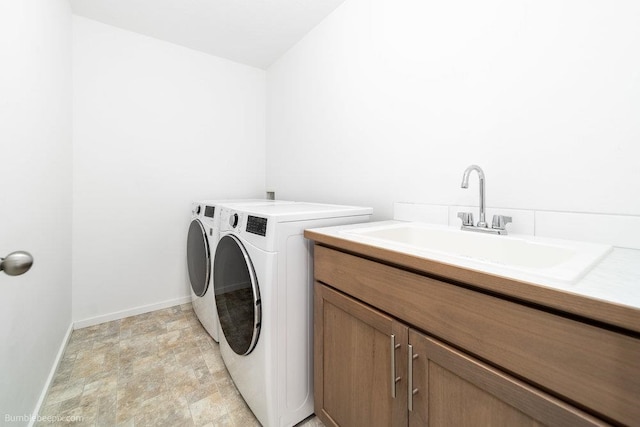 washroom with sink, cabinets, and washer and clothes dryer