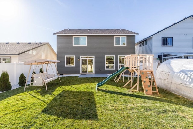 rear view of house featuring a yard and a playground