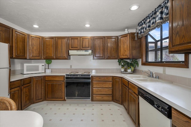 kitchen with white appliances, a textured ceiling, and sink